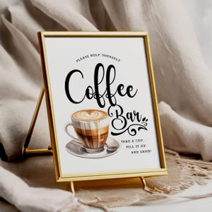 Op de afbeelding: Een goudkleurig ingelijst bord met de woorden "Coffee Bar" in elegant schrift. Het bord toont een aquarel illustratie van een koffiekopje met latte art. De tekst "Please help yourself, take a cup, fill it up, and enjoy!" is ook opgenomen.