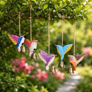 Peut inclure: Cinq ornements d'oiseaux en bois peints à la main suspendus à des ficelles en jute. Chaque oiseau présente un schéma de couleurs unique incluant le rose, le bleu, le violet et l'orange, avec une petite cloche en métal couleur laiton.