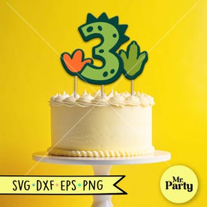 Pu&ograve; includere: Una torta di compleanno con glassa bianca e un cake topper verde con il numero 3. Il numero 3 ha un tema dinosauro con accenti arancioni e verdi. La torta &egrave; su un supporto bianco su sfondo giallo. Le parole "SVG DXF EPS PNG" sono in basso a sinistra.