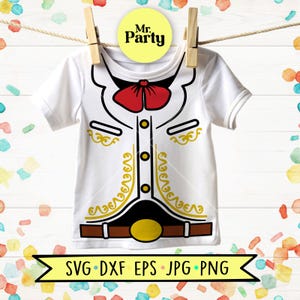 May include: A white short-sleeve t-shirt featuring a graphic print of a mariachi jacket with a red bow tie, gold filigree details, black trim, and a brown belt with a gold buckle. The shirt is displayed on a clothesline with wooden clips.