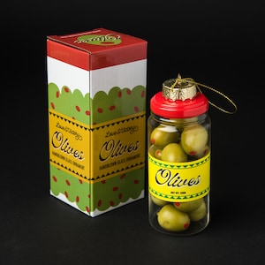 Pu&ograve; includere: Un ornamento natalizio in vetro a forma di barattolo di olive, con coperchio rosso e tappo dorato. Il barattolo &egrave; pieno di olive verdi con puntini rossi. Una scatola abbinata con la scritta "Olives" e "Handblown Glass Ornament".