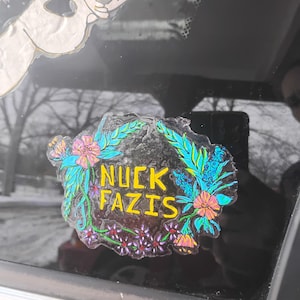 May include: A sticker with a floral wreath design and the text "NUCK FAZIS" in yellow letters.