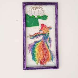 May include: A framed stained glass artwork featuring a rainbow-colored fish swimming near a white water lily with green leaves.