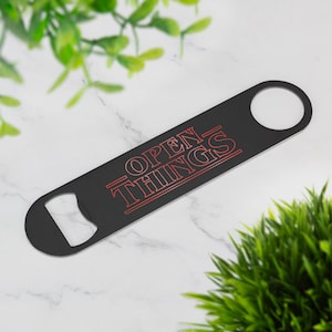 May include: Black metal bottle opener with a red "Open Things" inscription, inspired by the popular TV show Stranger Things.