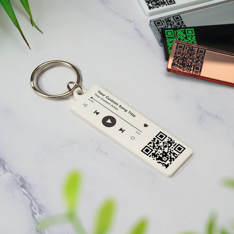 May include: White keychain with a black and white QR code, play button, and the text "Your Custom Song Title" and "Your Custom Artist".