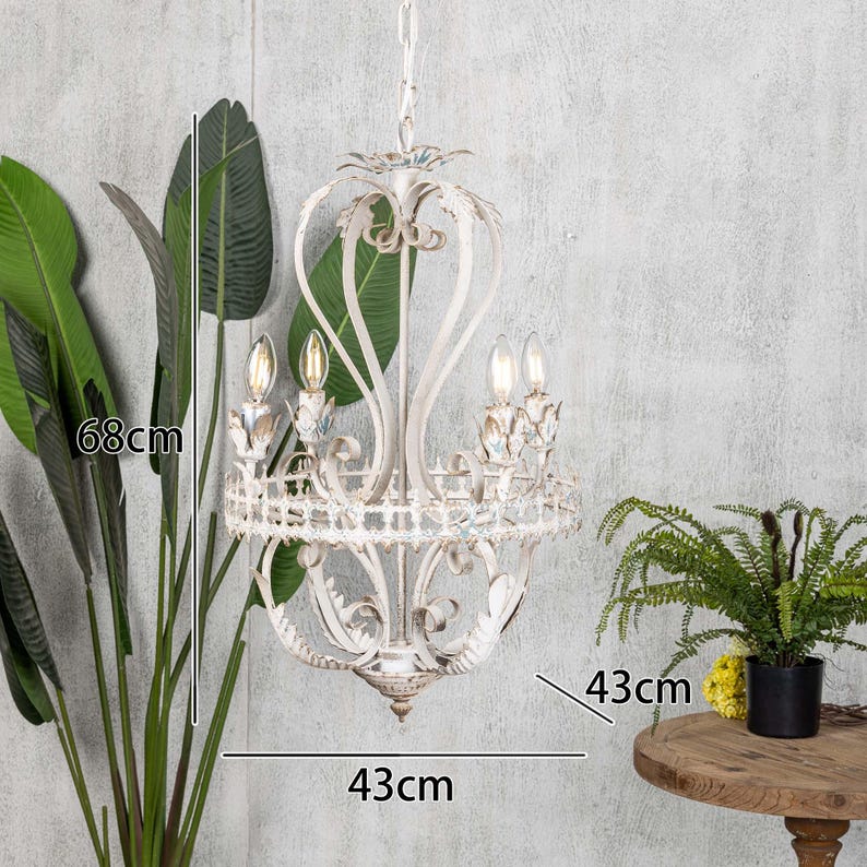 May include: White metal chandelier with ornate detailing and five light bulbs. The chandelier is 43 inches wide and 68 inches tall.