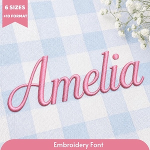 May include: The name Amelia is embroidered in pink thread in a cursive script font on a light blue and white gingham fabric. A pink banner in the top left corner displays the text 6 SIZES + 10 FORMAT, and a pink banner at the bottom says Embroidery Font.