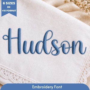 May include: A white fabric swatch featuring the blue embroidered name Hudson in a cursive script font. A blue banner in the top left corner displays the text 6 SIZES BX +10 FORMAT, and a blue banner at the bottom displays Embroidery Font.