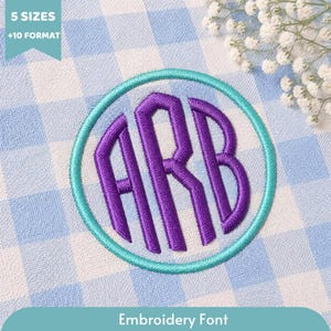 May include: A circular embroidery design featuring the purple monogram letters ARB enclosed within a teal border. The design is stitched onto a light blue and white gingham fabric. A teal banner in the corner displays 5 SIZES +10 FORMAT.