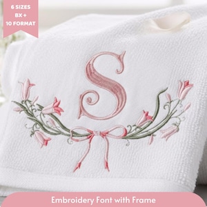 Könnte beinhalten: Weißes Handtuch mit einem gestickten rosa Buchstaben "S" in dekorativer Schrift. Der Buchstabe ist von einem floralen Design mit rosa Blüten und grünen Stielen umgeben. Der Text "Embroidery Font with Frame" befindet sich unten.