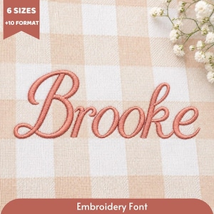 Può includere: Il nome Brooke è ricamato con filo rosa polvere in un carattere corsivo. Il ricamo è centrato su un tessuto a quadretti vichy beige chiaro e bianco. Un piccolo banner nell'angolo in alto a sinistra riporta la scritta 6 SIZES +10 FORMAT.