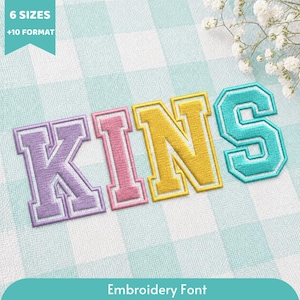 Peut inclure: Un motif de police de broderie épelant le mot KINS en lettres majuscules de style universitaire. La lettre K est violet clair, le I est rose, le N est jaune et le S est bleu sarcelle. Chaque lettre présente un contour épais et un motif de point texturé.