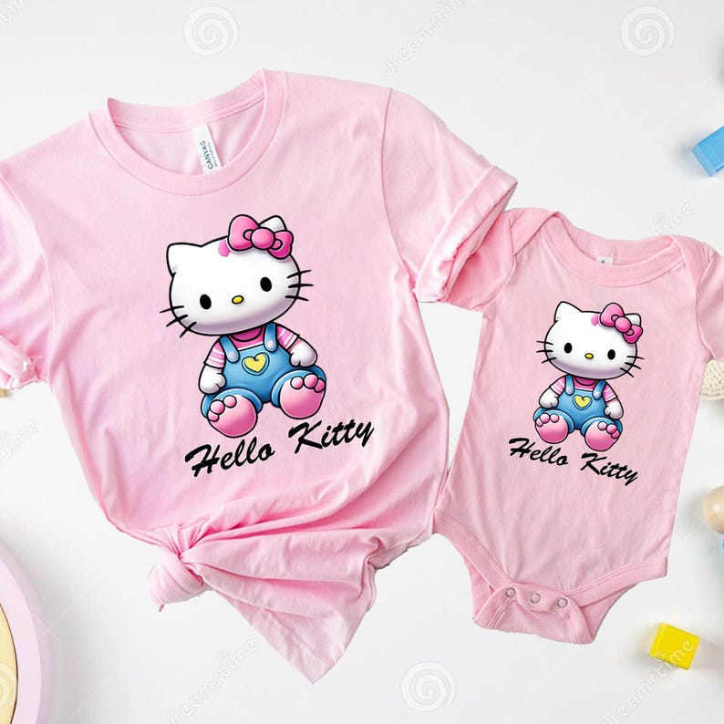 以下が含まれることがあります： ピンクのハローキティのTシャツとボディースーツのセット。Tシャツには、オーバーオールとピンクのリボンをつけたハローキティのグラフィックが描かれています。ボディースーツには、同じグラフィックが描かれていますが、サイズは小さくなっています。