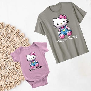 以下が含まれることがあります： ハローキティのプリントが施されたTシャツ2枚セット。大きい方のTシャツはグレーで、白いハローキティのプリントと「ハローキティ」の文字が書かれている。小さい方のTシャツはピンクで、白いハローキティのプリントと「ハローキティ」の文字が書かれている。