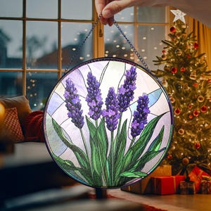 May include: A stained glass window hanging with a round frame and a design of purple lavender flowers with green leaves on a white background.