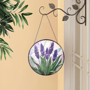 May include: A stained glass suncatcher featuring a purple lavender flower design. The suncatcher is round and hangs from a metal hook.