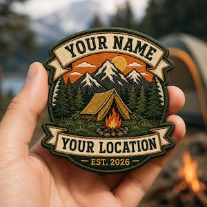 May include: A circular embroidered patch featuring a mountain landscape with a tent and campfire. The design includes banners with the text YOUR NAME and YOUR LOCATION, and the text EST. 2026 at the bottom. The colors include green, orange, and white.