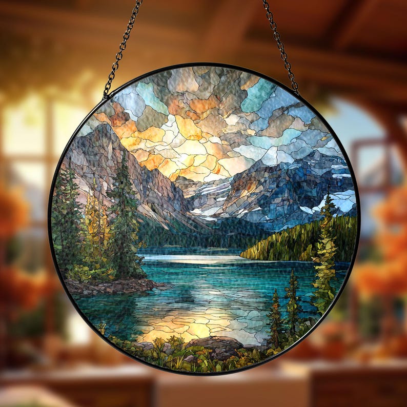 May include: Round stained glass panel depicting a mountain lake scene with a colorful sky. The artwork features a black metal frame and a hanging chain. The landscape includes mountains, trees, and a lake with blue and green hues.