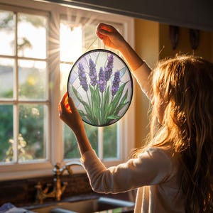 May include: A round stained glass window hanging with a purple and green lavender design.