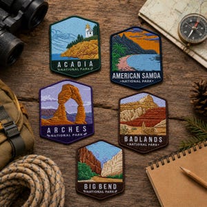 May include: Five hexagonal embroidered patches featuring landscapes of Acadia, American Samoa, Arches, Badlands, and Big Bend National Parks. Each patch displays a unique scene with text identifying the park name in white lettering on a dark base.