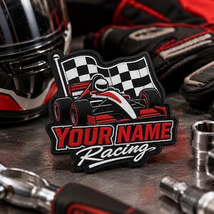 May include: A rectangular embroidered patch featuring a red and white race car in front of a black and white checkered flag. The text "YOUR NAME" is in bold red block letters, with the word "Racing" in white script underneath the car graphic.