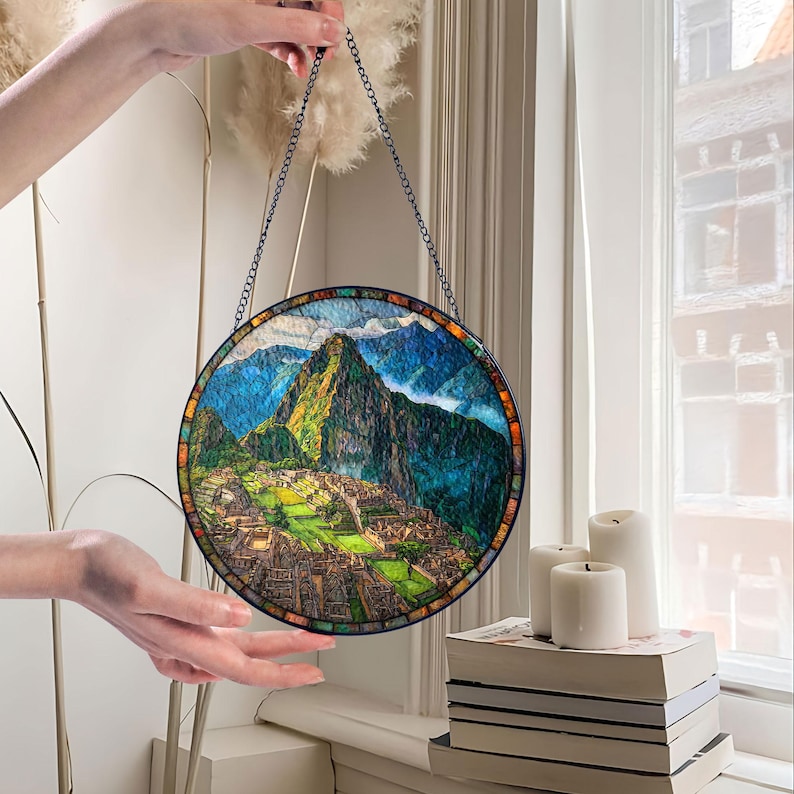 May include: Round stained glass panel depicting the Machu Picchu mountain landscape. The artwork features a detailed view of the ancient city with green and brown hues, framed by a mosaic border and a chain for hanging.