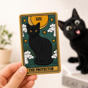 May include: A rectangular embroidered patch featuring a black cat sitting in the center of a dark green background. The design includes a yellow crescent moon, white clouds, and gold stars. The text XIII and THE PROTECTOR are stitched in gold.