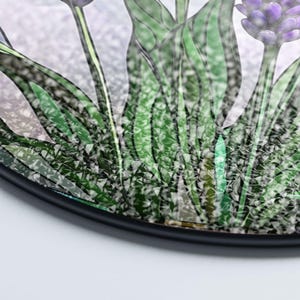 May include: A close-up of a stained glass window depicting a bouquet of purple flowers with green leaves. The glass has a textured, iridescent finish.