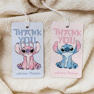 Puede incluir: Dos etiquetas de regalo con personajes de dibujos animados. Una etiqueta es azul claro con un personaje rosa, la otra es rosa con un personaje azul. Ambas etiquetas tienen las palabras "THANK YOU" y "with love, Madison".