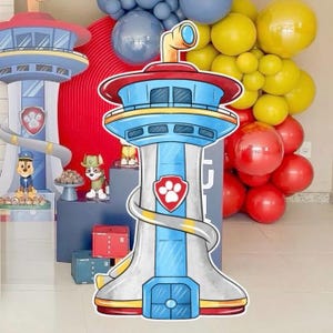 Può includere: Decorazione a tema Paw Patrol con un design a torre, con una parte superiore rossa e blu, una base bianca e un emblema a impronta di zampa. La scena comprende palloncini gialli, rossi e blu e statuette di personaggi.
