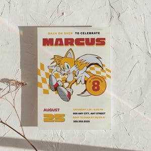 Può includere: Un invito per una festa di compleanno con il personaggio Tails di Sonic the Hedgehog. L'invito riporta il nome "Marcus" a grandi lettere rosse, con i dettagli della festa, tra cui data, ora e luogo. L'invito è su sfondo crema.