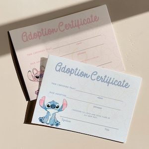 May include: Two adoption certificates with the text "Adoption Certificate" in pink and blue script. One certificate features a pink cartoon character, and the other features a blue cartoon character. Both have lines for filling in information.