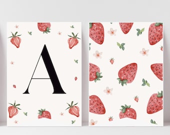 May include: Two framed art prints featuring a strawberry theme. One print displays a large black letter "A" surrounded by watercolor strawberries and leaves. The other print showcases a pattern of strawberries, flowers, and leaves on a white background.