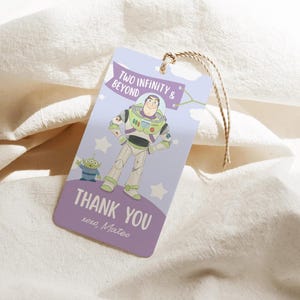 May include: A lavender gift tag featuring Buzz Lightyear and an alien from Toy Story. The tag reads "Two Infinity & Beyond" and "Thank You xoxo, Mateo". A brown string is attached for hanging.