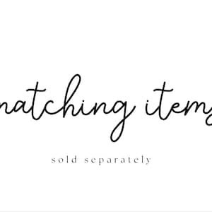 Puede incluir: Fondo blanco con las palabras "matching items" en fuente cursiva. Debajo, en una fuente m&aacute;s peque&ntilde;a, sin serifa, se lee "sold separately". El texto es negro.