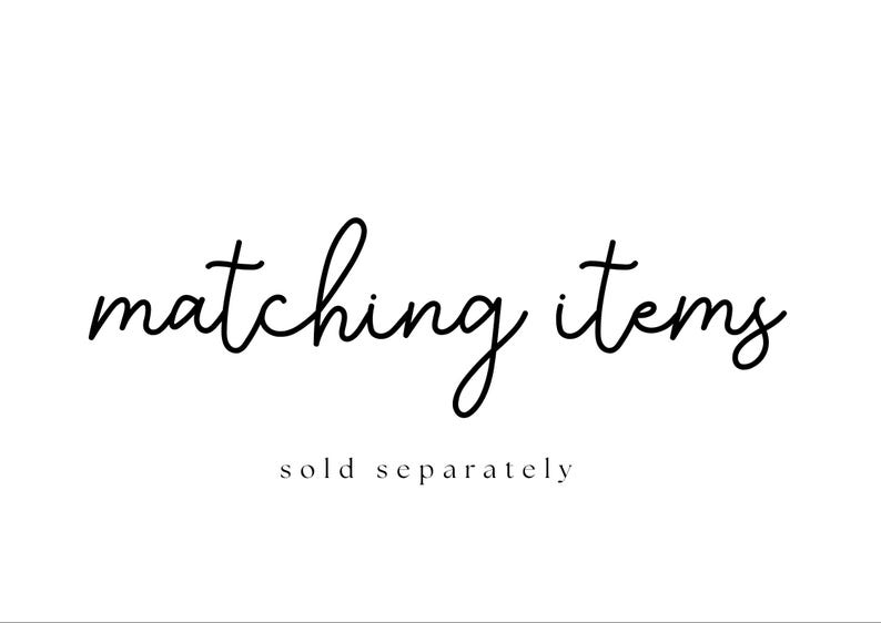 Puede incluir: Fondo blanco con las palabras "matching items" en fuente cursiva. Debajo, en una fuente m&aacute;s peque&ntilde;a, sin serifa, se lee "sold separately". El texto es negro.