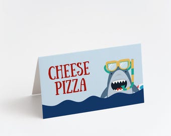 May include: A light blue folded card with the words "CHEESE PIZZA" in red. A cartoon shark wearing goggles and a snorkel is in the lower right corner, above blue waves. The card is on a white background.
