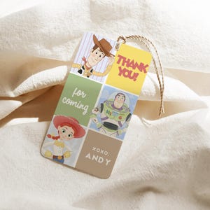 May include: A rectangular gift tag featuring cartoon characters Woody, Buzz Lightyear, and Jessie from Toy Story. The tag has the words "Thank You!" and "for coming" printed on it, along with "XOXO. ANDY". A brown string is attached.