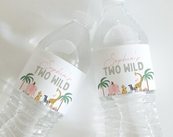 Puede incluir: Dos botellas de agua de plástico transparente con etiquetas blancas. Las etiquetas dicen "Sophia's TWO WILD" en escritura rosa y gris. Las etiquetas presentan ilustraciones de un elefante rosa, una jirafa, una cebra y palmeras. Las botellas están llenas de agua.
