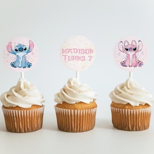 Puede incluir: Tres cupcakes con glaseado blanco y adornos decorativos. Los adornos presentan personajes de dibujos animados y el texto "MADISON TURNS 7". Los cupcakes est&aacute;n sobre una superficie blanca.