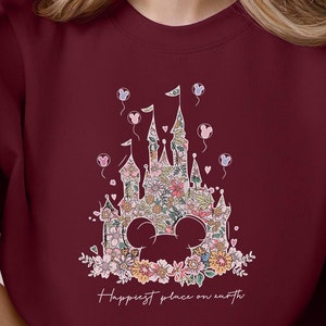 Puede incluir: Sudadera color granate con un dise&ntilde;o floral del castillo de Cenicienta y el texto "Happiest place on earth".