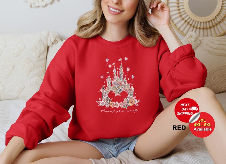 Puede incluir: Sudadera roja con un gr&aacute;fico blanco de un castillo con flores y el texto "Happiest place on earth".
