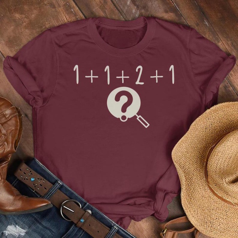 May include: Burgundy t-shirt with a white graphic of a magnifying glass over a question mark and the equation 1+1+2+1.