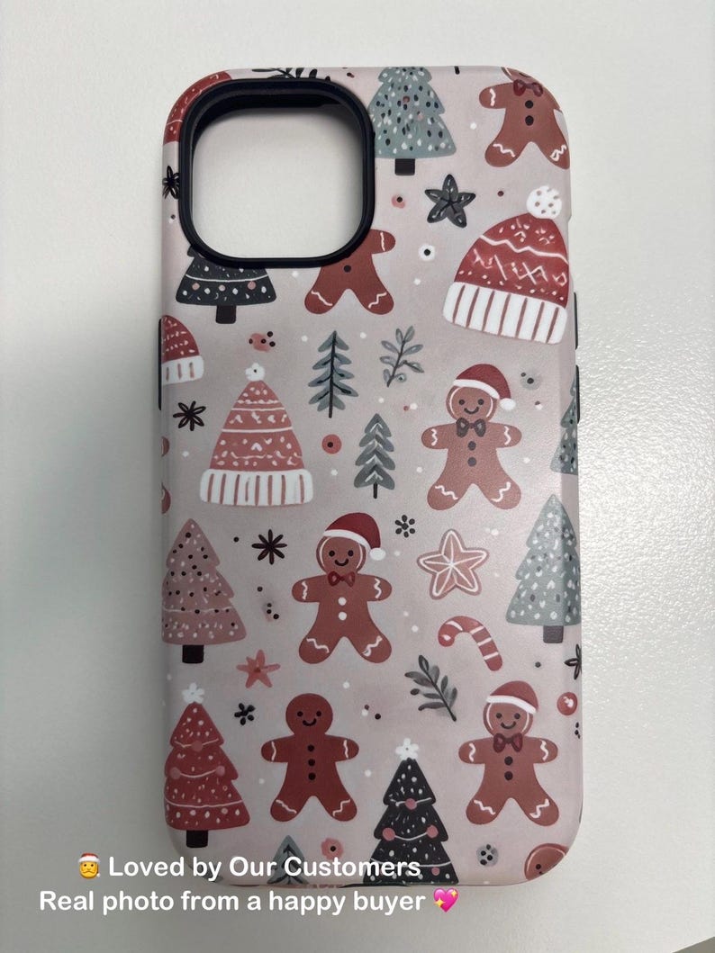 Customer photo of the Gingerbread Christmas Phone Case with pink background, featuring gingerbread men, candy canes, and holiday trees. Real product photo from buyer.