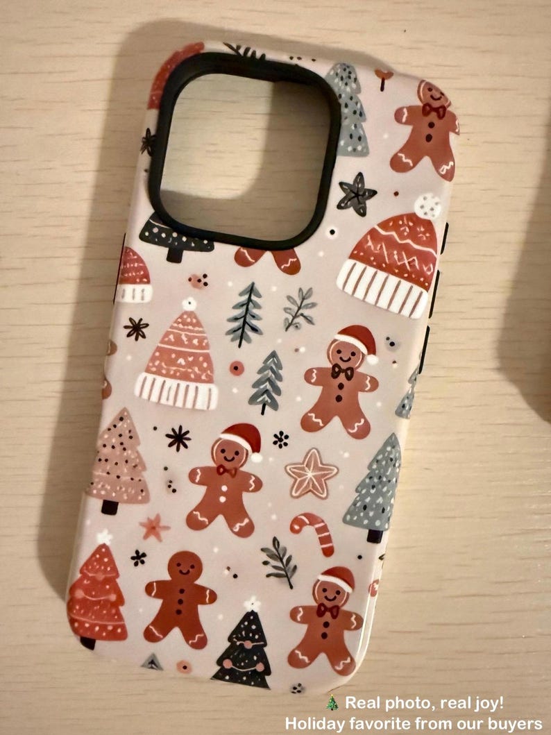 Customer photo showing the Cute Pastel Gingerbread Christmas phone case — festive beige background with gingerbread men, Christmas trees, and holiday hats. High-quality protective case with adorable pastel design.