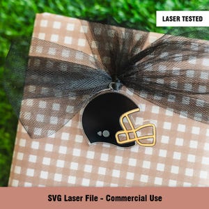May include: A black and gold football helmet SVG laser cut file for commercial use. The helmet is on a brown and white checkered background with black tulle.