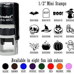 May include: A black and gray Trodat Printy 4612 stamp with various Halloween-themed mini stamps. The stamps include a bat, tombstone, the word "BOO!", a cat in a witch hat, a skull, a witch hat, a jack-o'-lantern, a potion bottle, a bat, a cauldron, a pumpkin, and a voodoo doll. Available in eight ink colors.