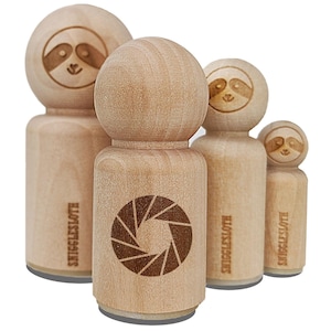 May include: A collection of wooden stamps with a light brown finish. The stamps feature a sloth face design and a circular aperture design. The text "SNIGGLESLOTH" is printed on the side of the stamps.
