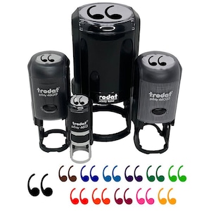 May include: A collection of black quote stamps in various sizes, with the brand name "trodat" visible on the sides. Below the stamps are examples of quote marks in various colors, including black, brown, blue, and green.