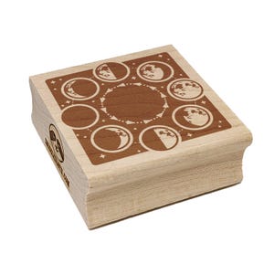 May include: A wooden stamp featuring a brown design of the phases of the moon. The stamp has a square shape with rounded edges. The phases of the moon are arranged in a circular pattern around a central circle. The stamp has the text "www.etsy.com" on the side.